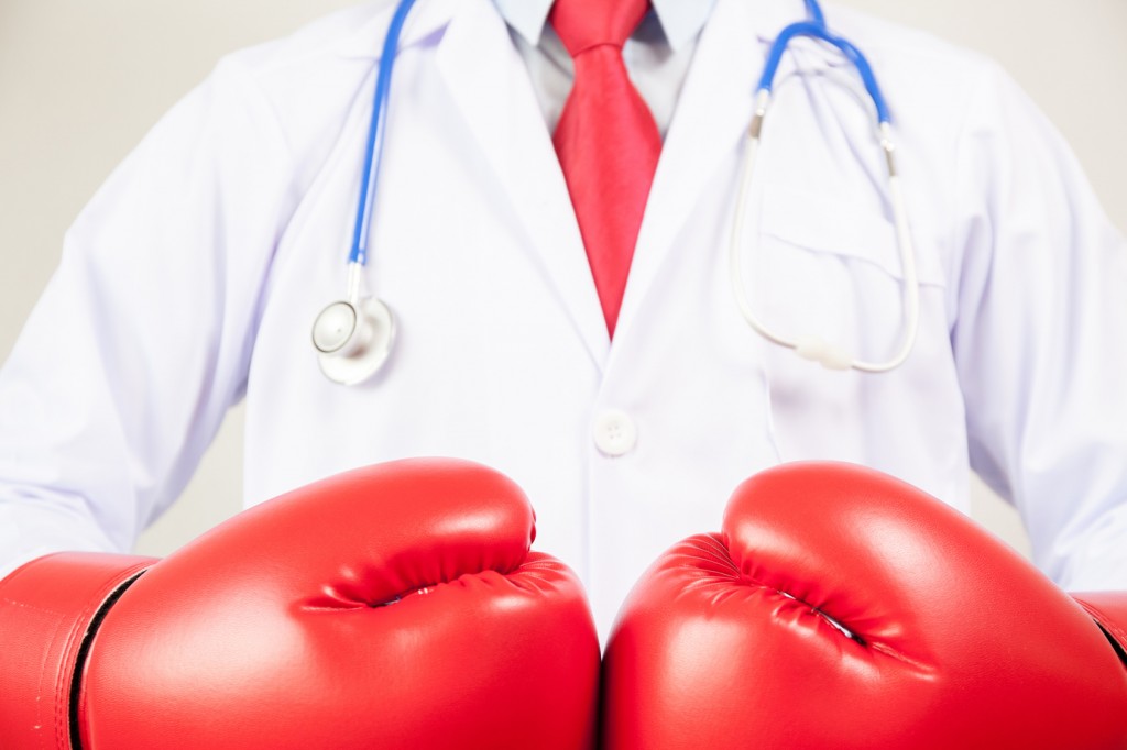 Doctor wearing boxing gloves in white background
